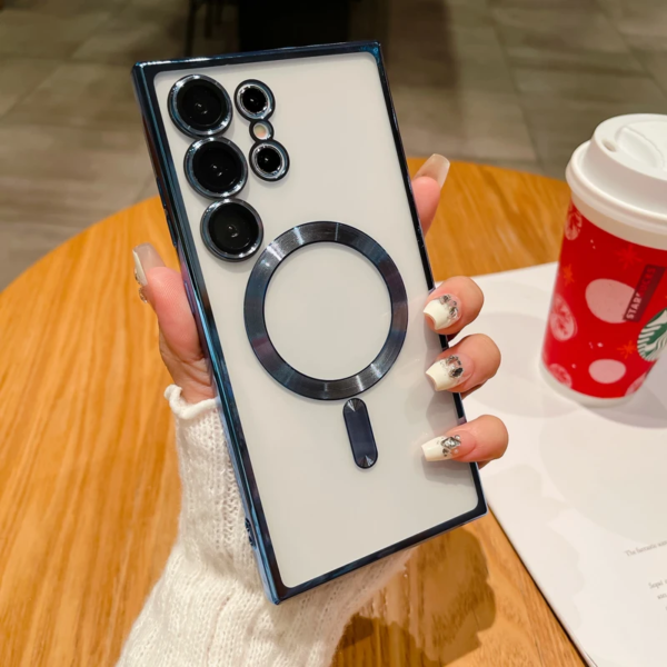A person's hand with decorated fingernails holding a smartphone with multiple camera lenses, next to a Starbucks cup on a table.